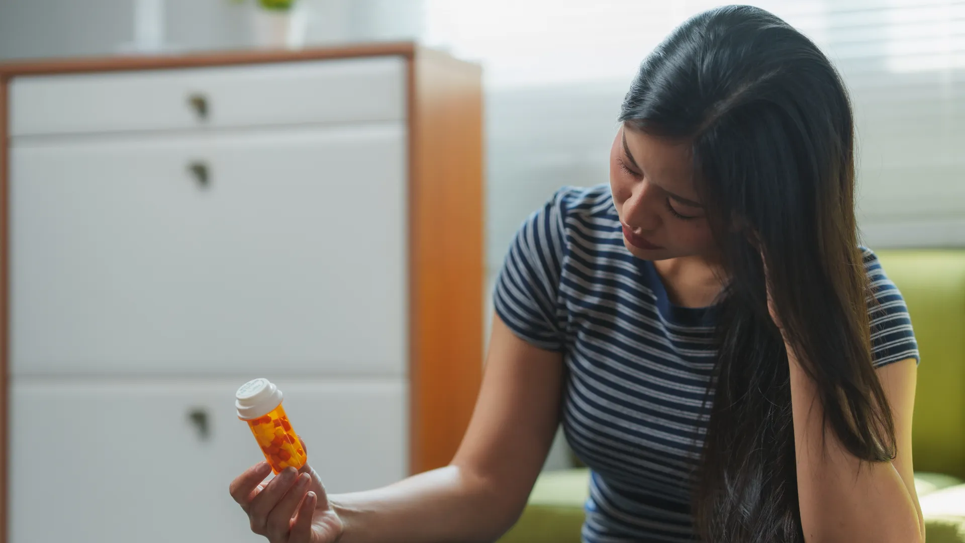 young-woman-feeling-sad-and-holding-a-pill-bottle